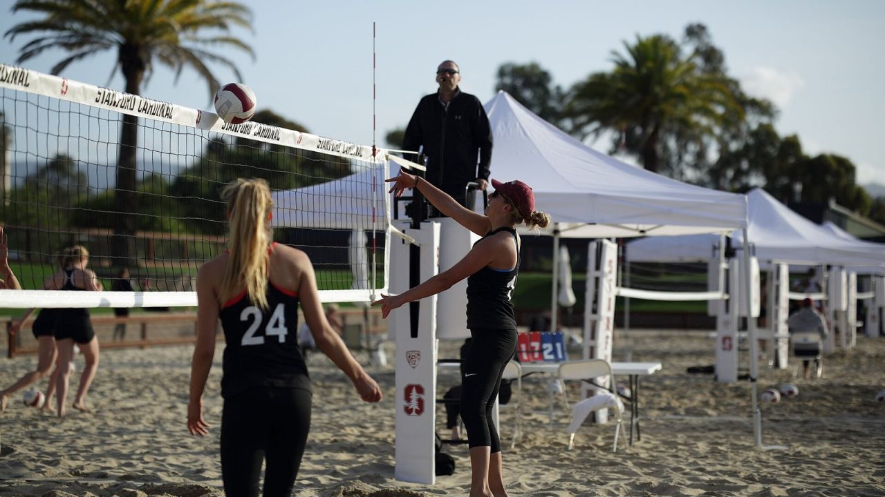 Two Stanford beach volleyball players in action on sand during a 2016 NCAA match