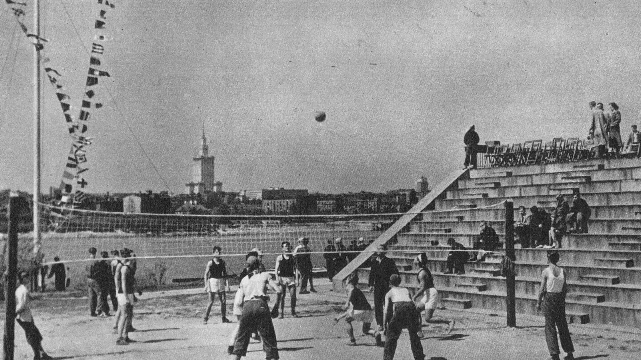 Black-and-white photo of an outdoor volleyball match at a riverside YMCA ground in Warsaw in the 1950s