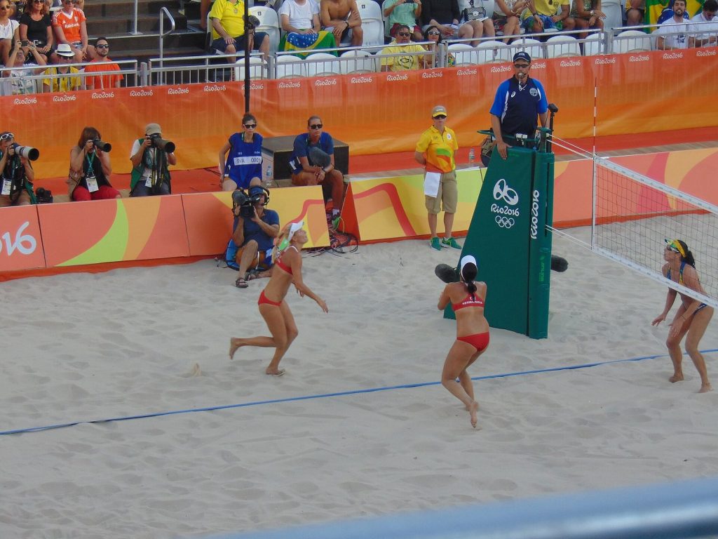 Women's beach volleyball pairs playing on sand in front of photographers at the Rio 2016 Olympics